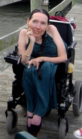 Photograph of Harriet McBryde Johnson seated in her power wheelchair on a wooden dock.